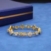 Gold-tone four-leaf clover bracelet with round and square stone settings and a box clasp.