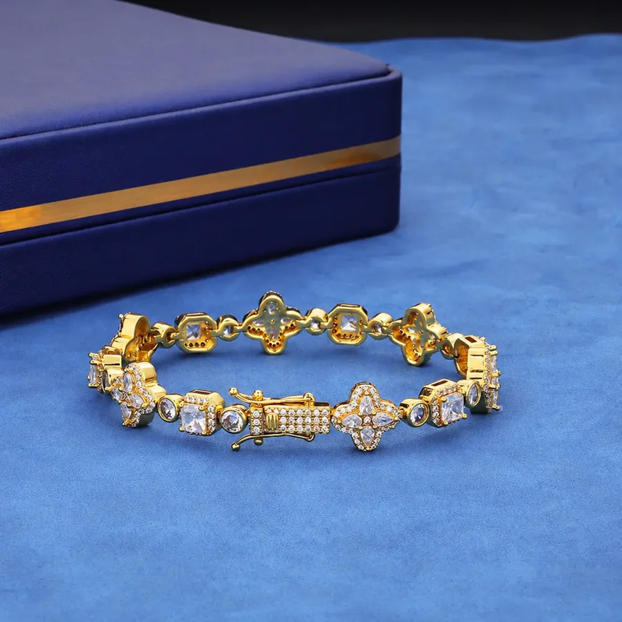 Gold-tone four-leaf clover bracelet with round and square stone settings and a box clasp.